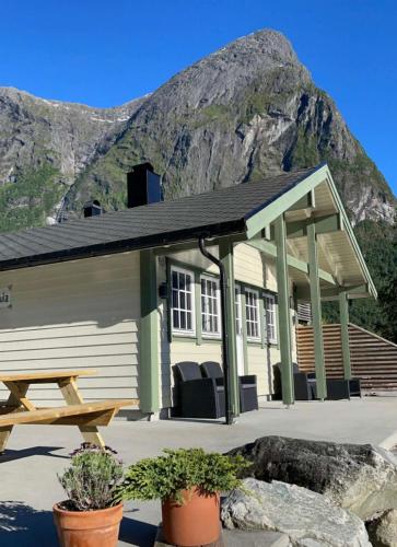 a building with a picnic table in front of a mountain at Vollsnes Feriehus in Hjelle