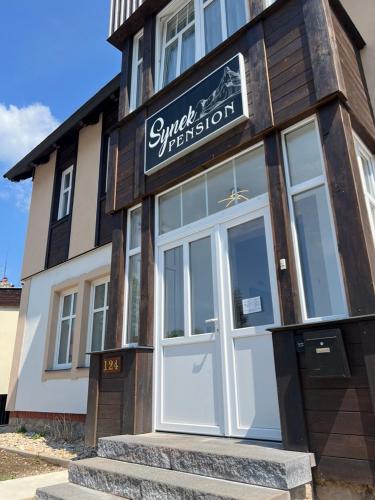 a building with a storefront with a white door at SYNEK Pension in Špindlerův Mlýn