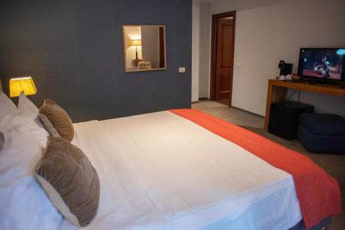 a bedroom with a large white bed and a television at Paj Hotelul Retreat & Spa in Sinaia