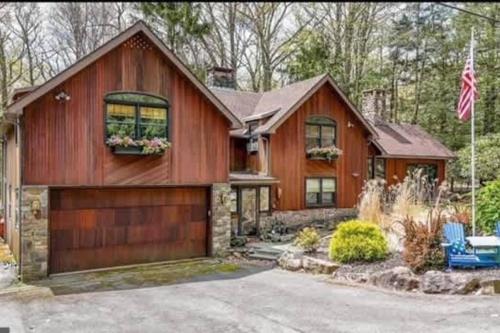 a wooden house with a garage and a flag at The HYLANDS - Stunning Unique Mountain Home - Spa in Lake Harmony