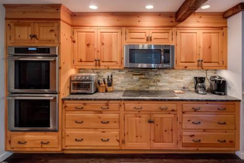 a kitchen with wooden cabinets and stainless steel appliances at The HYLANDS - Stunning Unique Mountain Home - Spa in Lake Harmony