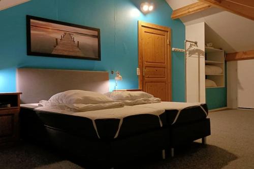 a large bed in a bedroom with a blue wall at Vakantievilla Värmland, Zweden in Filipstad