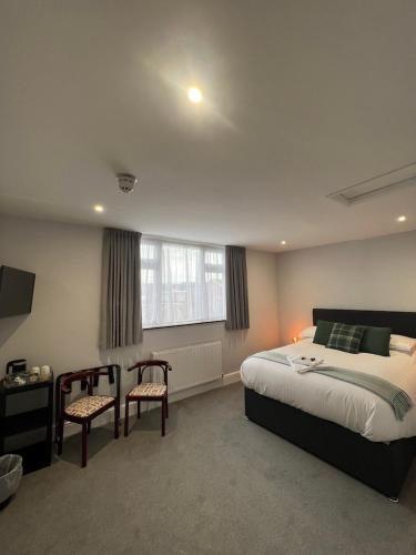 a bedroom with a bed and two chairs and a window at Brynhyfryd Guest House in Cardigan