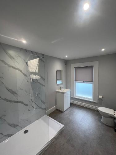 a bathroom with a tub and a sink and a toilet at Brynhyfryd Guest House in Cardigan