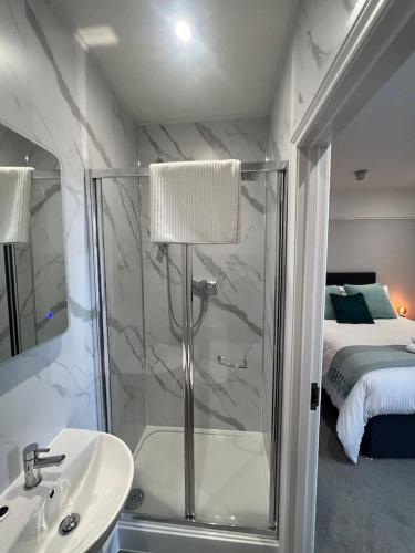 a bathroom with a shower and a sink and a bed at Brynhyfryd Guest House in Cardigan