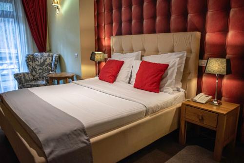 a hotel room with a large bed with red pillows at Paj Hotelul Retreat & Spa in Sinaia