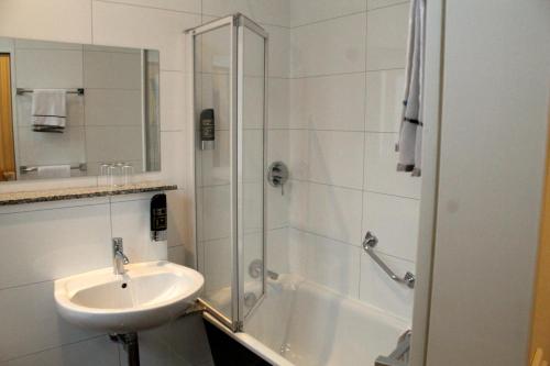 a white bathroom with a sink and a shower at Hotel Weidenhof in Düsseldorf