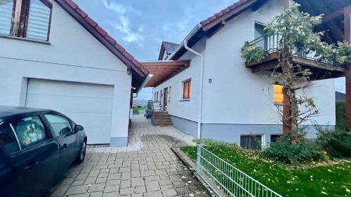 a car parked in front of a white house at Modernes Mini-Apartment in Kehl Kork in Kehl am Rhein