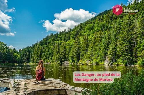 a woman standing on a wooden bridge over a lake at Le Pèlerin - Rustique Écoresponsable En nature in Notre-Dame-Des-Bois