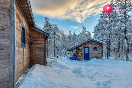 a log cabin in the snow next to a building at Le Pèlerin - Rustique Écoresponsable En nature in Notre-Dame-Des-Bois
