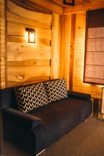 a black couch in a room with a wooden wall at Rich OAK - готель з відкритим панорамний басейном in Yablunytsya