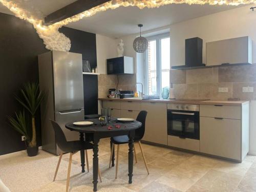 une cuisine avec une table avec des chaises et un réfrigérateur dans l'établissement Love Room romantique - Jacuzzi et Sauna intimes, à Villemur-sur-Tarn