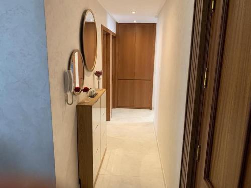 Appartement moderne avec vue panoramique في أغادير: حمام مع مغسلة مع مرآتين وممر