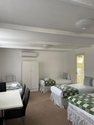 a room with three beds and a table and chairs at Euroa Motor Inn in Euroa
