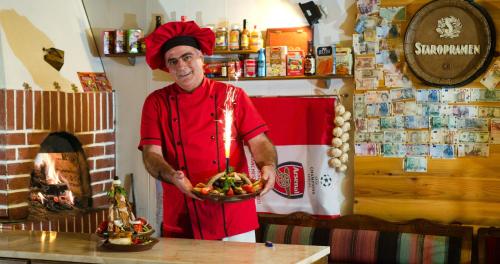 a man in a kitchen holding a bowl of food at Apartments & Studios Mountain Romance in Bansko