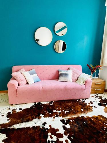 a pink couch in a living room with three mirrors at Appartamento Decanter in Tirano