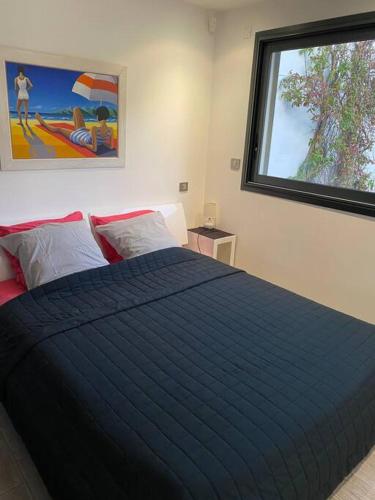 une chambre avec un lit avec une couette bleue et une fenêtre dans l'établissement Magnifique maison les pieds dans l eau, à Lumio