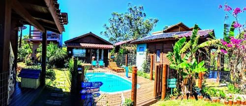 a house with a swimming pool in a yard at Chalés Praia do Rosa piscina compartilhada in Imbituba