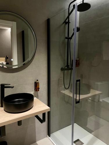 a bathroom with a glass shower with a black sink at Casual Fuentes in Bilbao