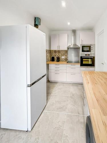 - une cuisine blanche avec un grand réfrigérateur blanc dans l'établissement Charmante dépendance avec jardin partagé, à Eaubonne