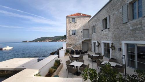 a building with tables and chairs next to the water at Marshal Hotel Heritage in Vis