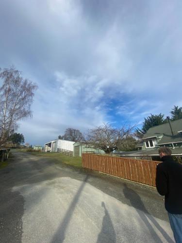 a man standing next to a fence on a street at Cherry Tree Cottage in Lawrence