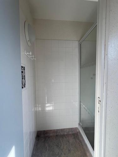 a white tiled shower with a glass door at Résidence des Carmes in Dol-de-Bretagne