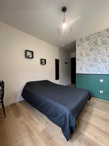 a bedroom with a bed with a blue bedspread at Résidence des Carmes in Dol-de-Bretagne