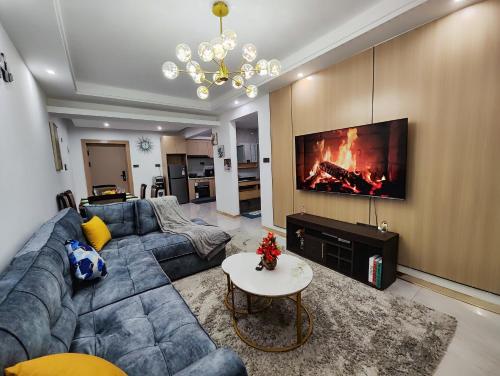 a living room with a blue couch and a fireplace at Lola's Haven - 75" Screen, Heated Pool, Gym, Views in Nairobi