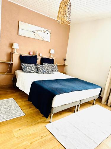 une chambre avec un grand lit avec des draps et des oreillers bleus dans l'établissement Le Perchoir Du Parc Cœur historique Anduze 3 Etoiles, à Anduze