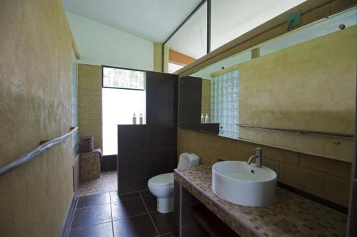 a bathroom with a sink and a toilet and a mirror at Canto de la Selva Jungle Lodge Selva Lacandona Chiapas in Galaxia