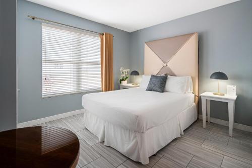 a bedroom with a large white bed and a window at Kasa La Flora and Impala Miami Beach in Miami Beach