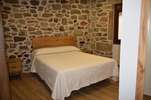 a bedroom with a bed in a stone wall at Alojamiento Rural La Josefa de los Arribes in Fermoselle