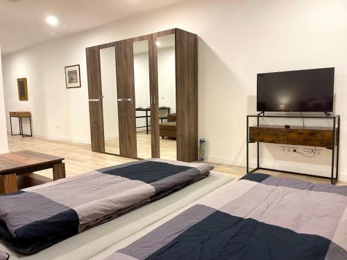 a bedroom with two beds and a flat screen tv at NEU Große Einzimmerwohnung im Zentrum Goldstadt Pforzheim Schlössle in Pforzheim