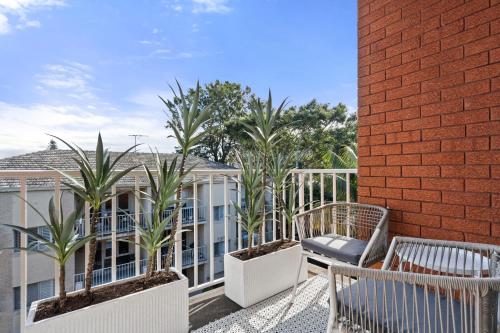 a balcony with two chairs and palm trees at Your Stylish Balmain Retreat in Sydney