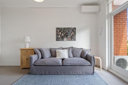 a gray couch in a living room with a window at Your Stylish Balmain Retreat in Sydney