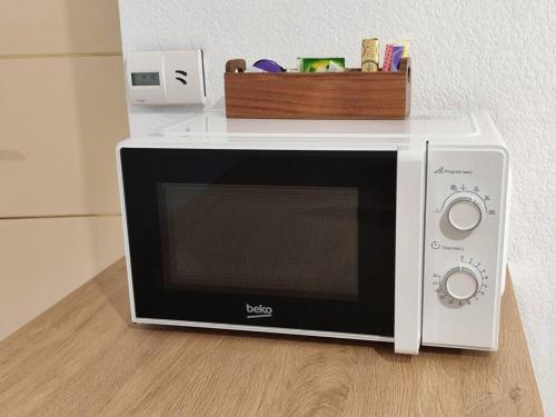 - un four micro-ondes blanc installé au-dessus d'un comptoir dans l'établissement Charmant Appartement Cozy, à Saint-Jory