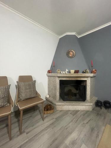 a living room with a fireplace and two chairs at Casa da Burra in Alijó