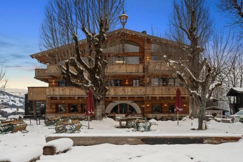 a large wooden building with snow on the ground at Das Kitz - Chalet Steuerberg XL Kitzbühel in Kitzbühel