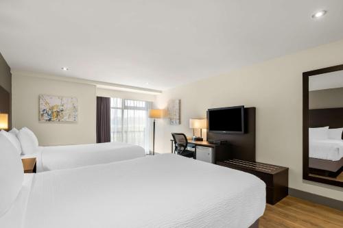 a hotel room with two beds and a flat screen tv at Best Western Hotel St. Jerome in Saint-Jérôme