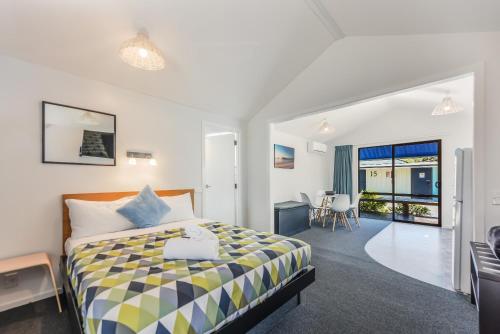a bedroom with a bed and a living room at Kaiteriteri Reserve Cabins in Kaiteriteri