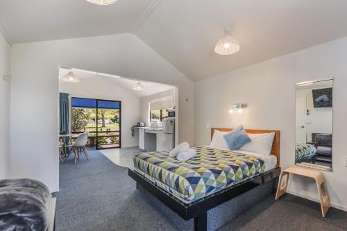 a bedroom with a bed and a living room at Kaiteriteri Reserve Cabins in Kaiteriteri