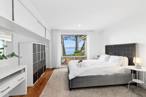 a white bedroom with a large bed and a window at Long Beach Hideaway in Long Beach