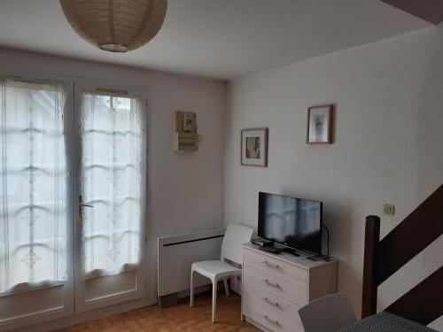- un salon avec une télévision et une chaise blanche dans l'établissement cottage duplex Villers sur mer 150 m de la plage, à Villers-sur-Mer