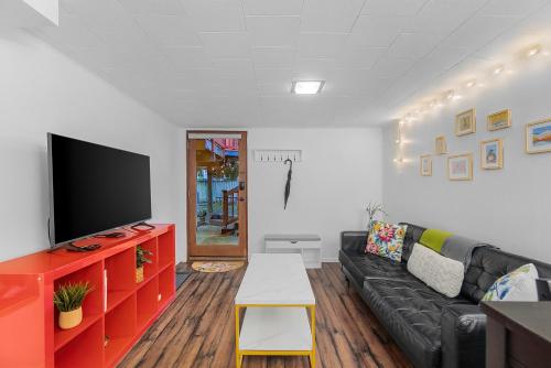 a living room with a black couch and a flat screen tv at Green Lake Zen Garden Basement in Seattle