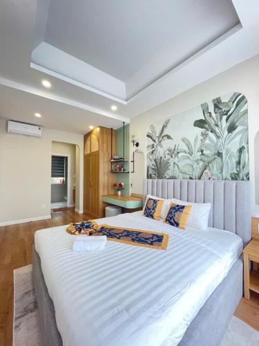 a bedroom with a large white bed with a painting on the wall at Villa IVY HOUSE in Bình Tú
