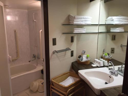 a bathroom with a sink and a tub and a toilet at Hotel New Omi in Omihachiman