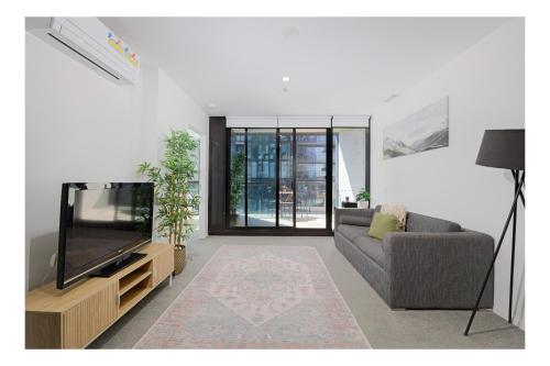 a living room with a television and a couch at Lakeside Luxe, Free parking, AIS, Spa, Gym, Sauna and Pool in Belconnen