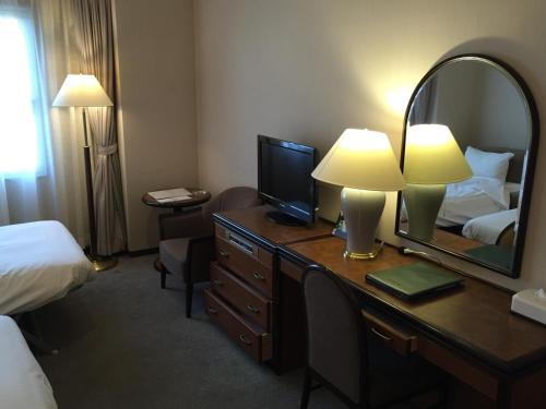 a hotel room with a bed and a desk with a mirror at Hotel New Omi in Omihachiman