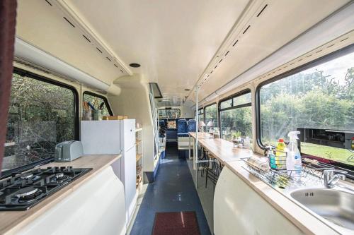 a kitchen in an rv with sinks and windows at Double Decker Bus on an Alpaca farm sleeps 8, 5 mins drive to Dartmoor in Bovey Tracey